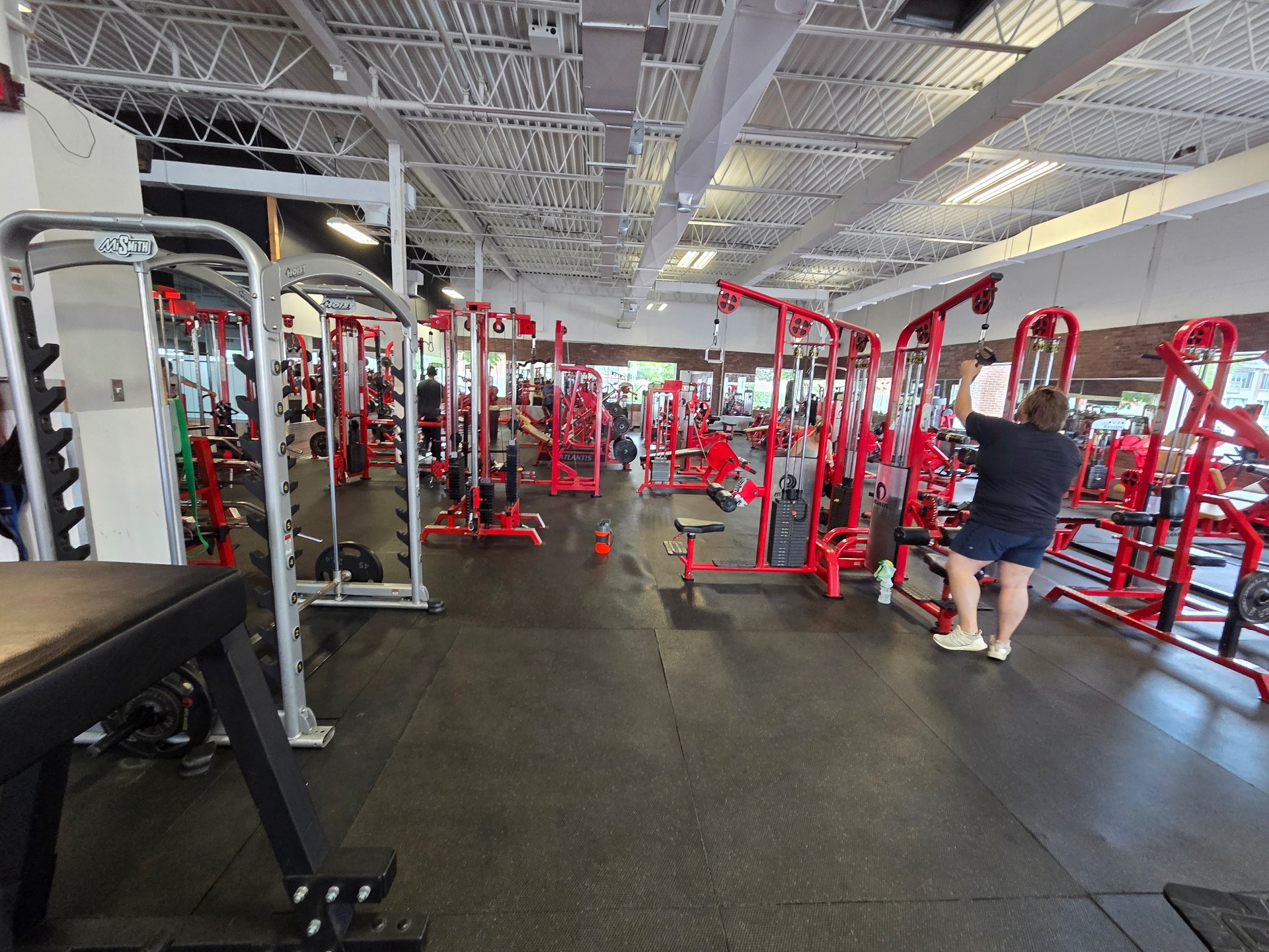 Vue large du plateau du Club Fitness à LaSalle, Montréal — membre au poste de câbles au milieu de l'équipement Atlantis rouge