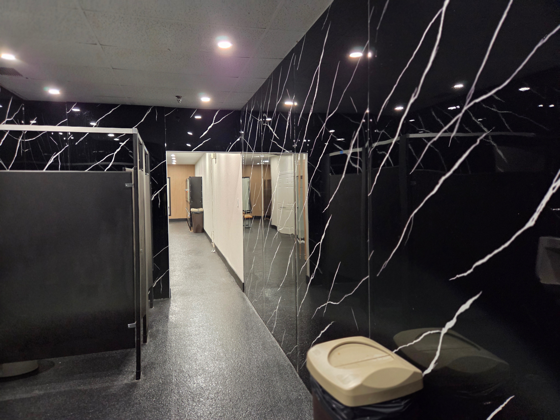 Salle de bain rénovée du Club Fitness à LaSalle, Montréal — murs en marbre noir veiné de blanc