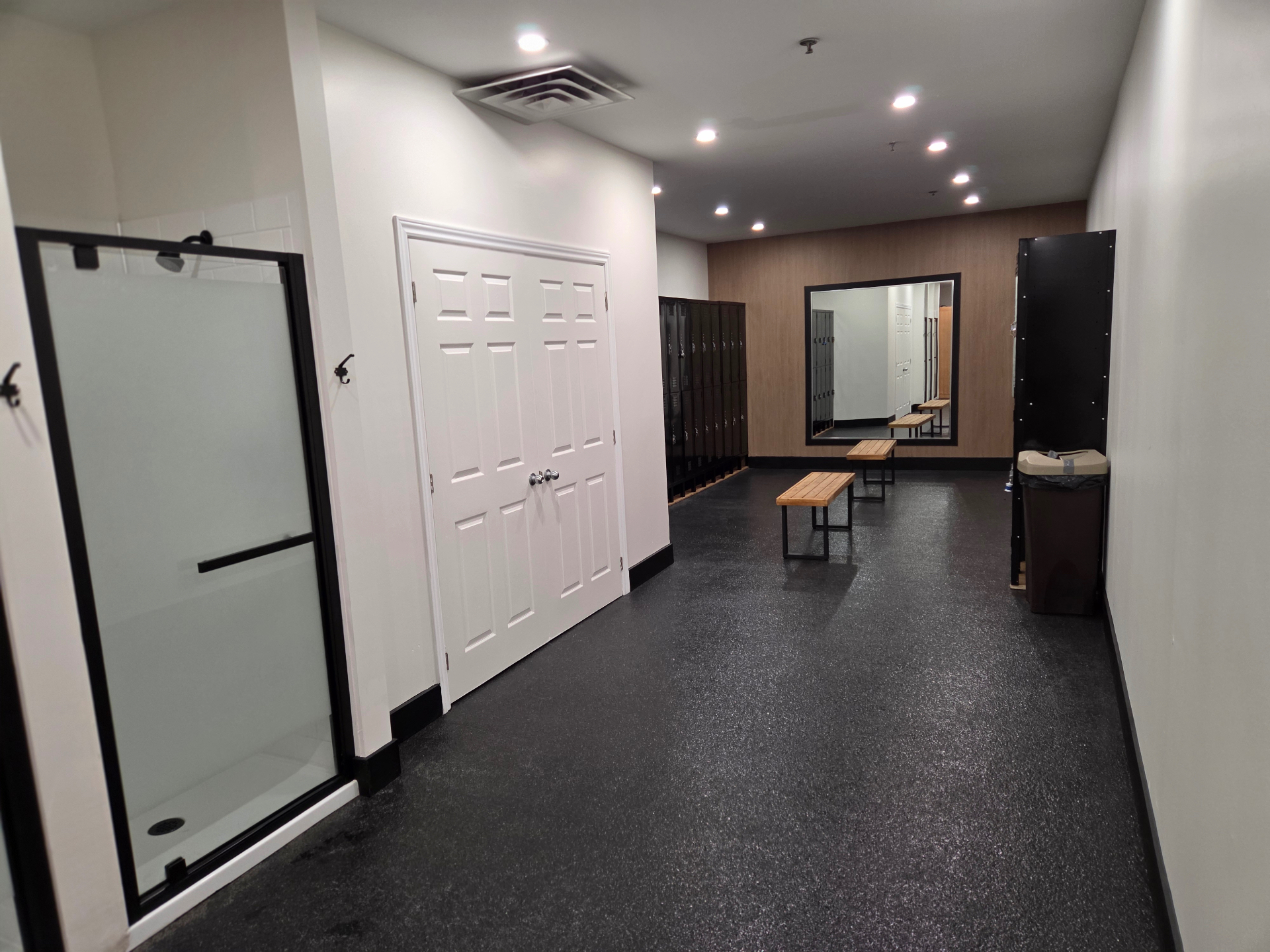 Vestiaire rénové du Club Fitness à LaSalle, Montréal — casiers noirs, bancs en bois et douche vitrée