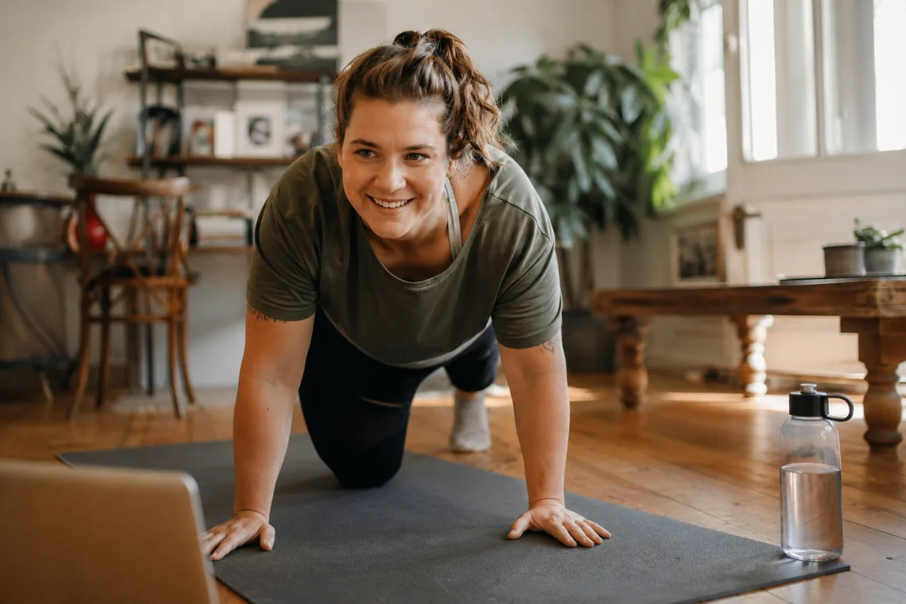 Personne s'entraînant à la maison sur un tapis de yoga dans une pièce lumineuse — Guide Kickstart 30 jours signé Le Club Fitness, Montréal